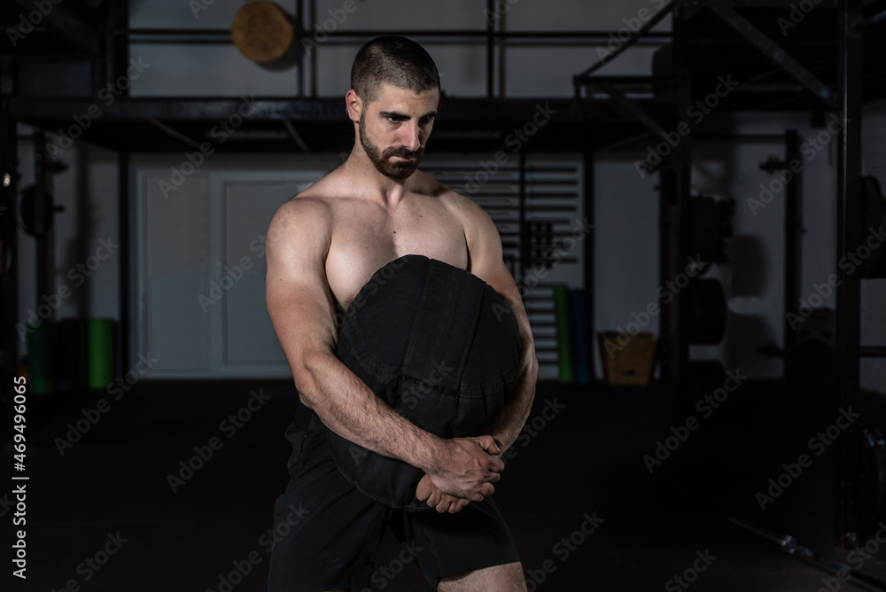 Young strong sweaty fit muscular man with big muscles holding