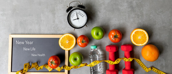 2021 and 2022 on alarm clock with workout planing for dieting. New Year New Life and New Health,  Sport exercise equipment workout andÂ gym nutrition fresh fruits for fitness