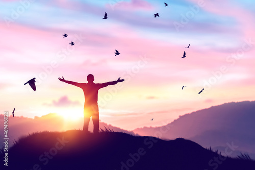 Man rising hands and birds flying on sunset sky at nature field abstract background. Freedom feel good and travel adventure concept.