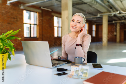 Middle age charming blond short haired businesswoman carrying Inspired maturelady remote worker student sit by laptop smiling at camera and think about discuss new plan idea. photo