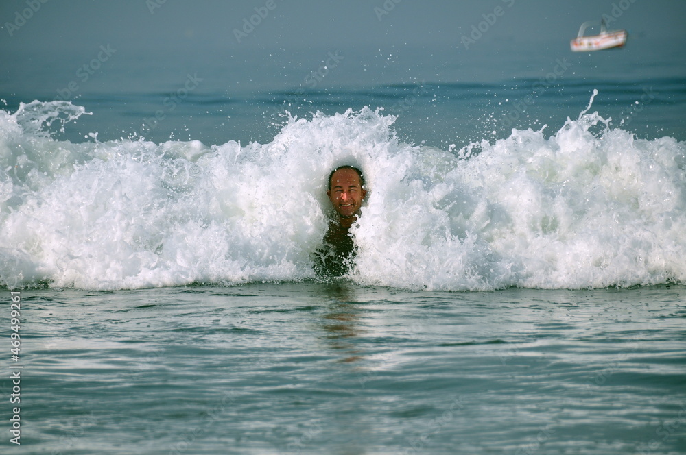 Happy adult man tourist having fun in Indian ocean with small splashing waves near coastline, Goa Happy adult man tourist having fun in Indian ocean with small splashing waves near coastline, Goa