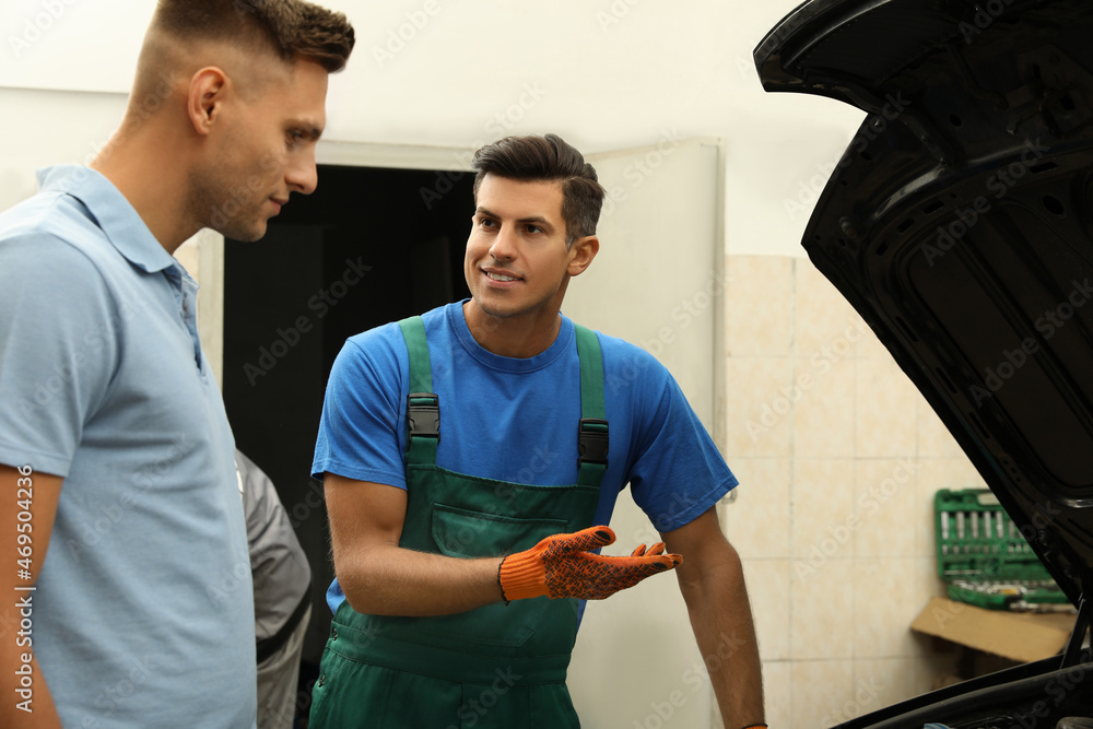 Obraz premium Mechanic and client near car at automobile repair shop