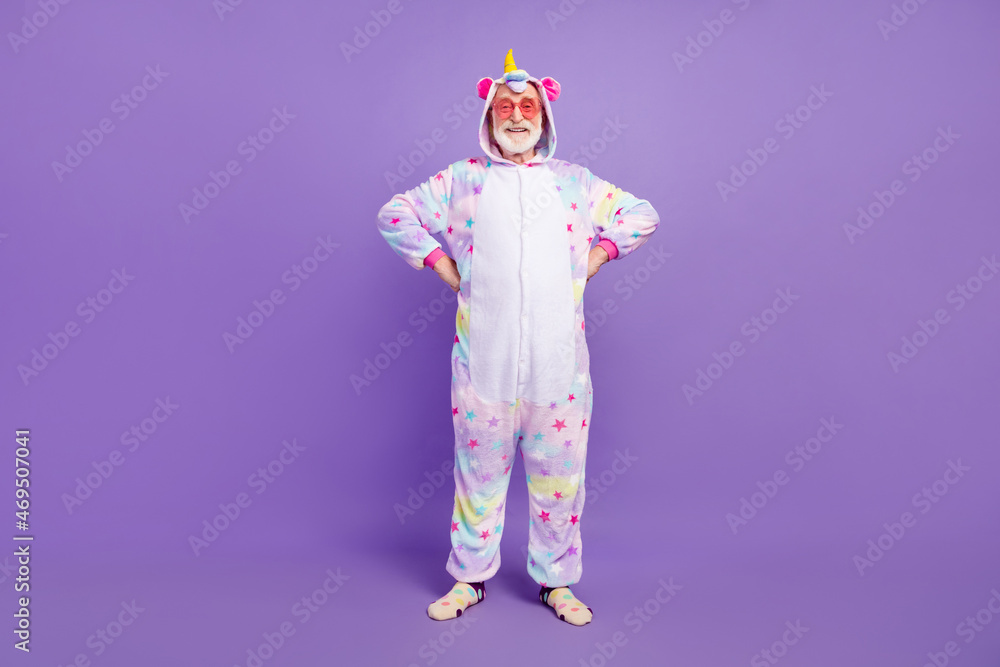 Photo of cool handsome man pensioner unicorn sleepwear dark glasses hands arms waist smiling isolated violet color background Photo of cool handsome man pensioner unicorn sleepwear dark glasses hands arms waist smiling isolated violet color background