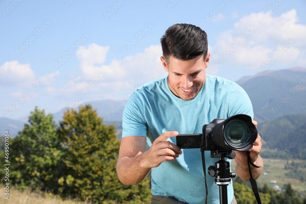 Professional photographer taking picture with modern camera in mountains Professional photographer taking picture with modern camera in mountains