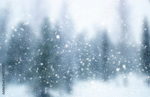 Blurred winter background. Falling snow on the background of an out-of-focus forest