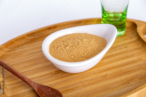 pot of Peruvian Maca powder under a bamboo tray, selective focus, on white background.