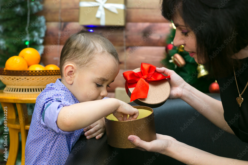 Mom and son disassemble a box with New Year gifts on the background of ...