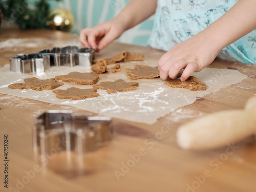 Close-up of children's hands cutting ginger cookies out of dough. Little girl making Christmas cookies. Christmas holidays, moments