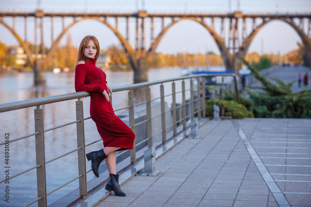 Red hair woman beautiful girl posing in a red dress on the street in ...