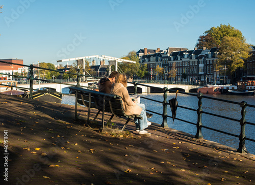 Canvas Print couple sitting on the bench near the river Amstel