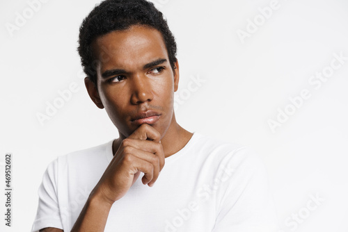 Young black man looking aside while holding his chin photo