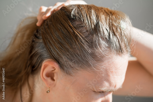 the woman shows the grown roots of gray hair. paint for gray hair.