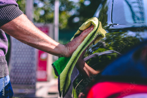 man's hand wipes the car with a microfibre towel