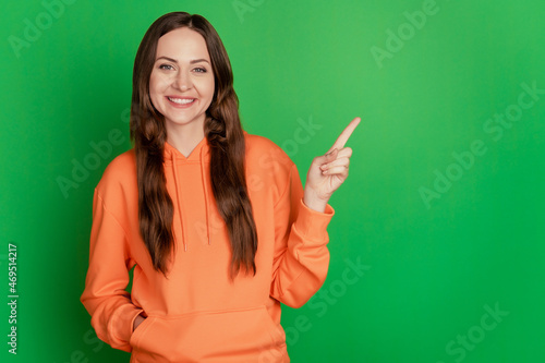 Portrait of funny promoter lady indicate finger empty space green background