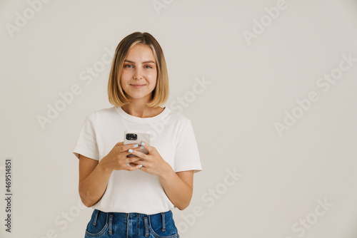 Young blonde woman smiling while using mobile phone