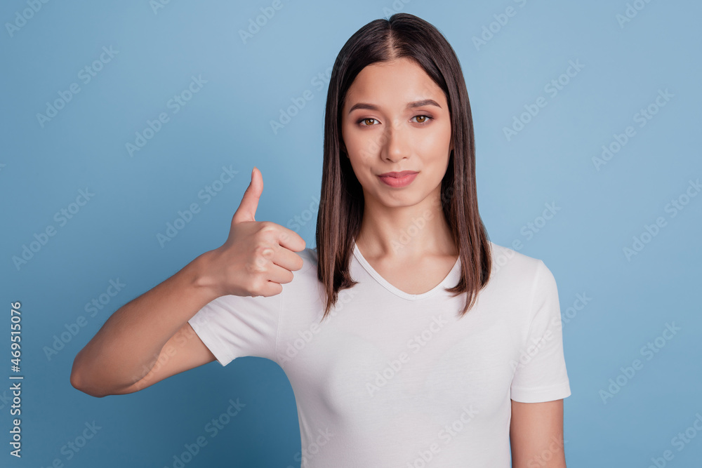 Photo of charming reliable cute positive girl raise thumb up look camera on blue background Photo of charming reliable cute positive girl raise thumb up look camera on blue background