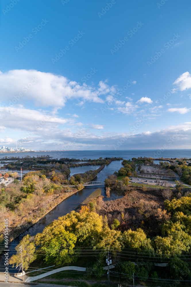 Drone views of Humber bay park  overlooking the lake  and fall tree colours by Parklawn and lakeshore  with blue sky and clouds 