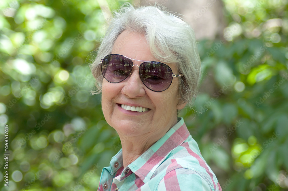 Beautiful white-haired lady smiling with blurry forest in the background Beautiful white-haired lady smiling with blurry forest in the background