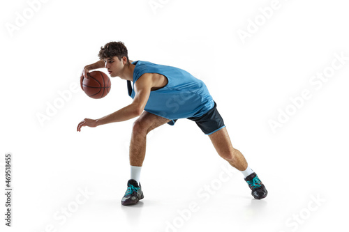 Full length portrait of basketball player practicing isolated on white studio background. Tall muscular athlete dribbling the ball.