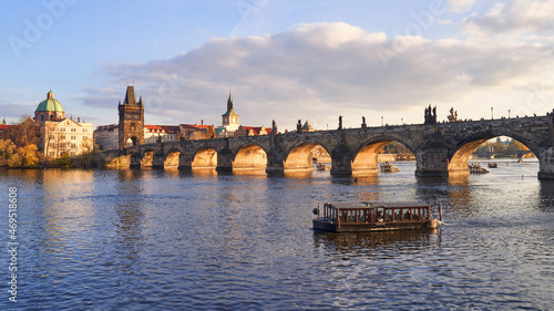 View of historical Charles Bridge that crosses the Vltava river in Prague, Czech Republic. Old Town Bridge Tower and a crossing boat visible.