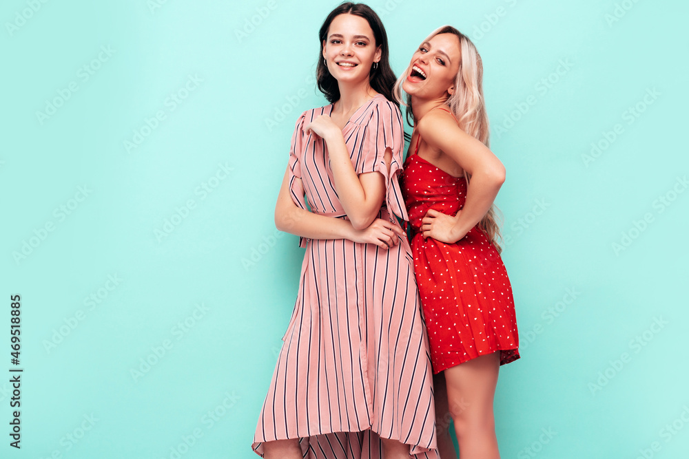 Two young beautiful smiling brunette hipster female in trendy summer clothes. Sexy carefree women posing near blue wall. Positive models having fun. Cheerful and happy Two young beautiful smiling brunette hipster female in trendy summer clothes. Sexy carefree women posing near blue wall. Positive models having fun. Cheerful and happy