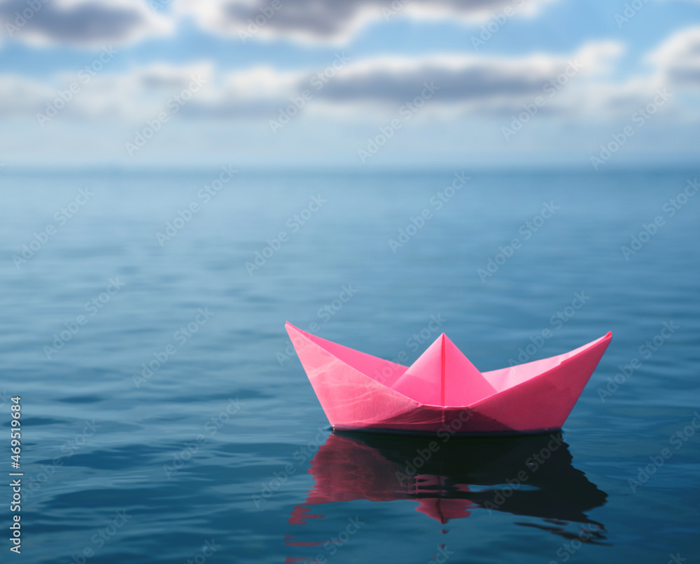 Pink paper boat floating on calm sea