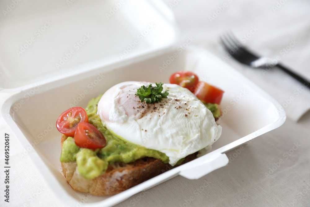 Poached eggs with avocado on toast with delivery package in white background