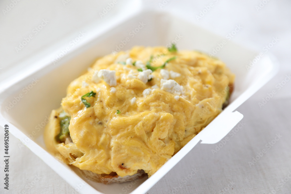 Avocado and scrambled eggs toast with delivery package in white background