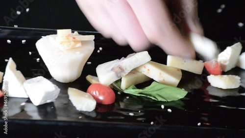 Close-up with two hands placing on a plate the different ingredients of an appetizer composed of grana padano cheese, cheese with olives, white cheese, pears, lettuce, olives and cherry tomato. photo