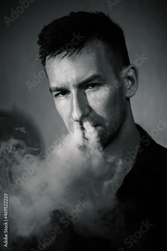 black and white portrait, brutal man exhales a lot of smoke from his nose