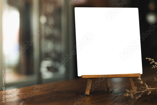 Menu with isolated white on wooden table on blurred coffee shop background.