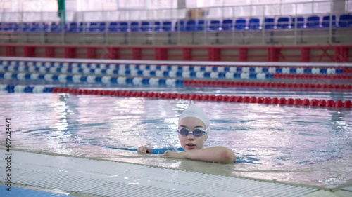 Amature woman in cap and goggles standing in the swimming pool after training before competition