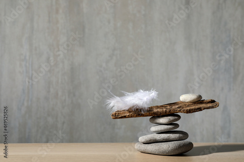 Sticker Stack of stones with tree branch and feather against grey background, space for text