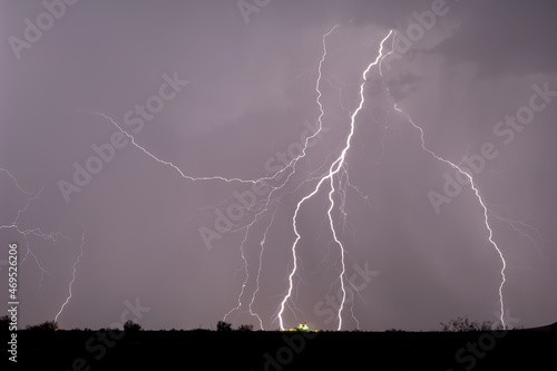 Multiple lightning strikes near and on a farm silo in the distance during a 2014 Arizona Monsoon storm.