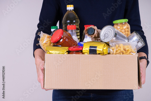 Woman volunteer hands holding food donations box with food grocery products photo