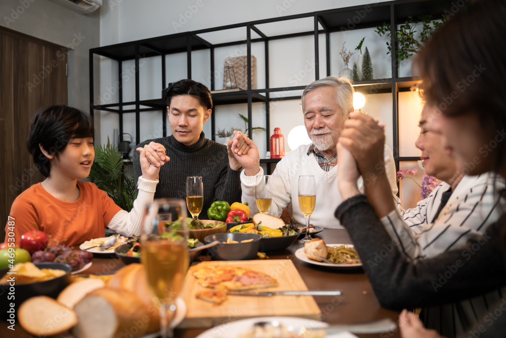 happiness asian multi generation family holding hands and praying on thanksgiving before holiday dinner.Thanksgiving Celebration Tradition asian Family Dinner Concept
