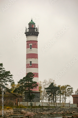 Red and white lighthouse on the rocky seashore. Vertical image. Maritime safety concept.