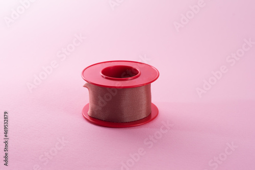 View of roll of medical or surgical tape for first aid on pink background. Silk tape. photo