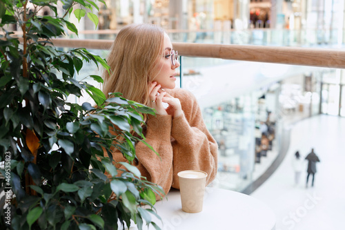 blonde girl in a shopping mall drinking coffee from a craft cup