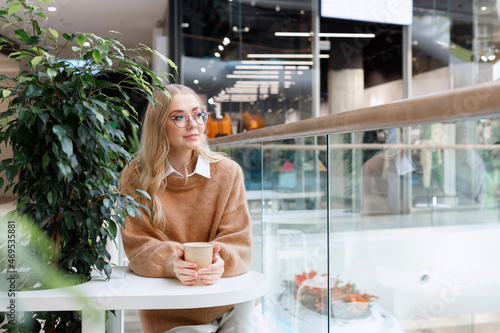 blonde model with a cup of coffee in a shopping mall on vacation