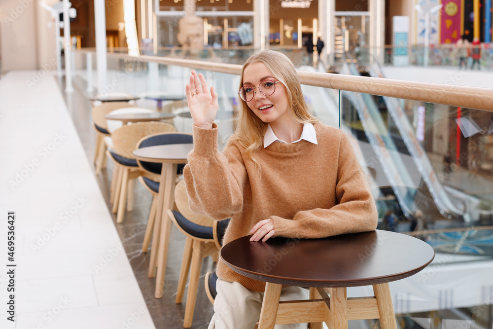 a young woman calls a waiter at a table in a shopping center