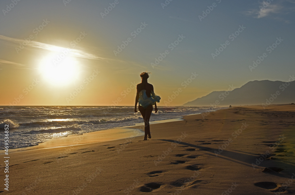 woman walking on the beach at sunset