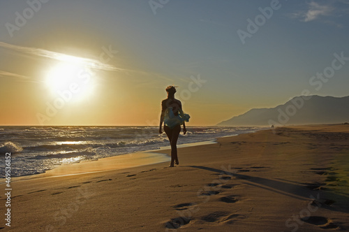 woman walking on the beach at sunset © Unusvita Media
