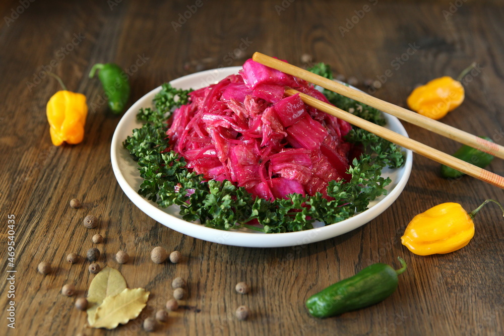 Korean cabbage salad with beets on a plate with pepper. Delicious Asian cusine Korean cabbage salad with beets on a plate with pepper. Delicious Asian cusine