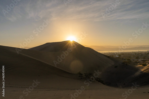 amanecer con sol brillante en cuidad con dunas de arena