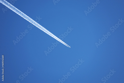 Jet airplane with white contrail. Trace of the high flying plane on the blue sky