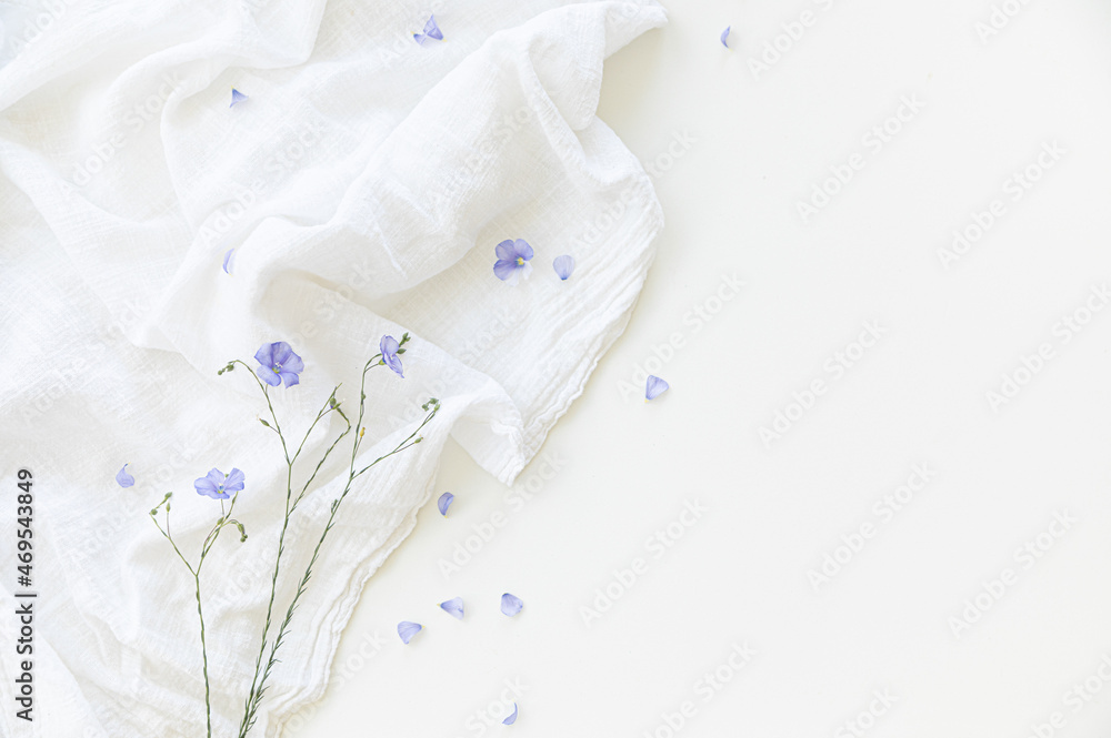 Blooming flax flowers on a white background on light-colored textiles. Blooming flax flowers on a white background on light-colored textiles.