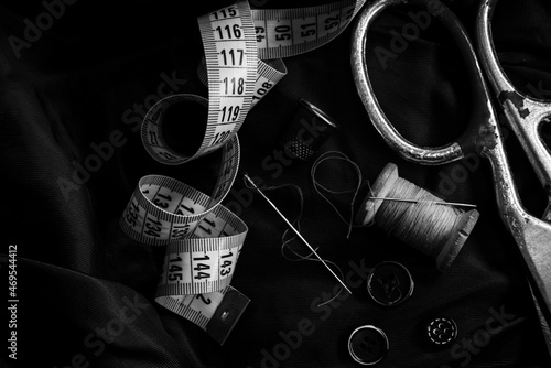 Retro tools for the work of a tailor, seamstress, fashion designer. Needle with thread, scissors, thimble, buttons and centimeter.