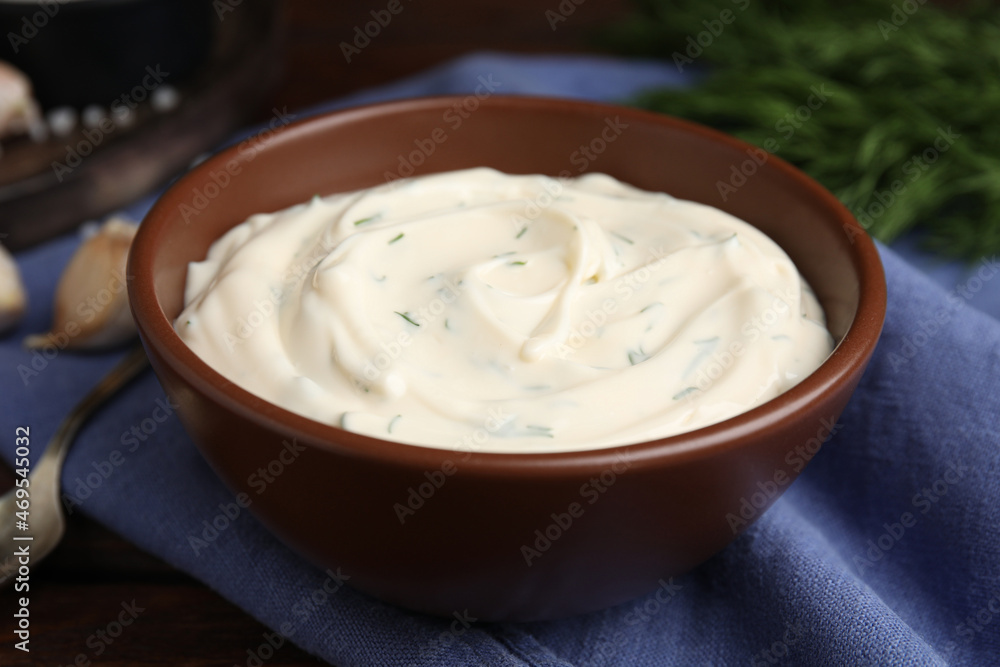 Tasty creamy dill sauce in bowl on blue kitchen towel, closeup Tasty creamy dill sauce in bowl on blue kitchen towel, closeup