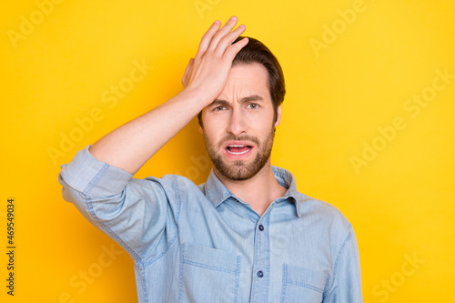 Photo portrait of young man touching head with hand forgot did mistake isolated on vivid yellow color background